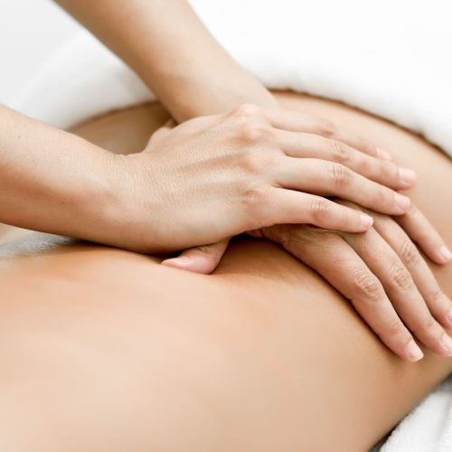 Young woman receiving a back massage in a spa center. Female patient is receiving treatment by professional therapist.